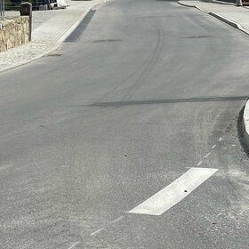 Neu asphaltierte Straße mit Bordstein und Gehweg